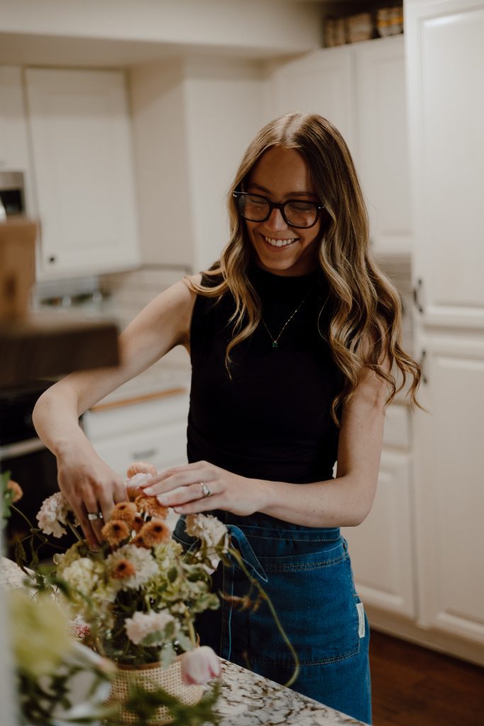 a woman in glasses cutting flowers
