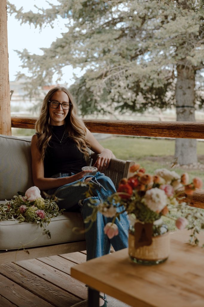 a woman sitting on a bench with flowers and a cup of coffee